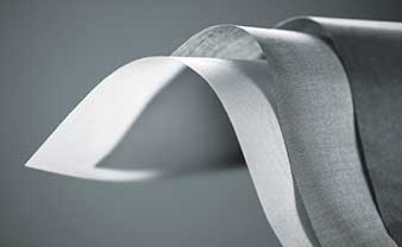 Close-up of a rolled material with a white layer curving outward from darker gray layers.