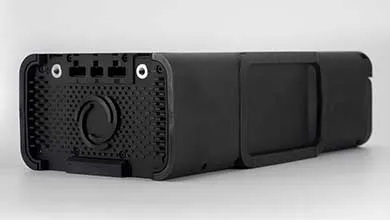 Rear view of a long, black electronic device with a perforated panel, central dial, and multiple ports.