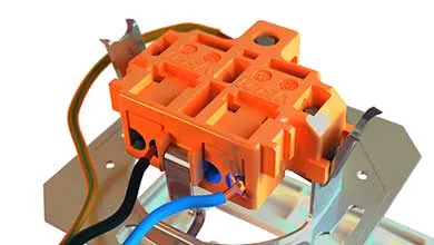 Close-up of an orange electrical component on a metal rail, with blue, black, and green-yellow wires attached.