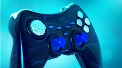 Black video game controller with blue joysticks and silver buttons on a bright blue background.