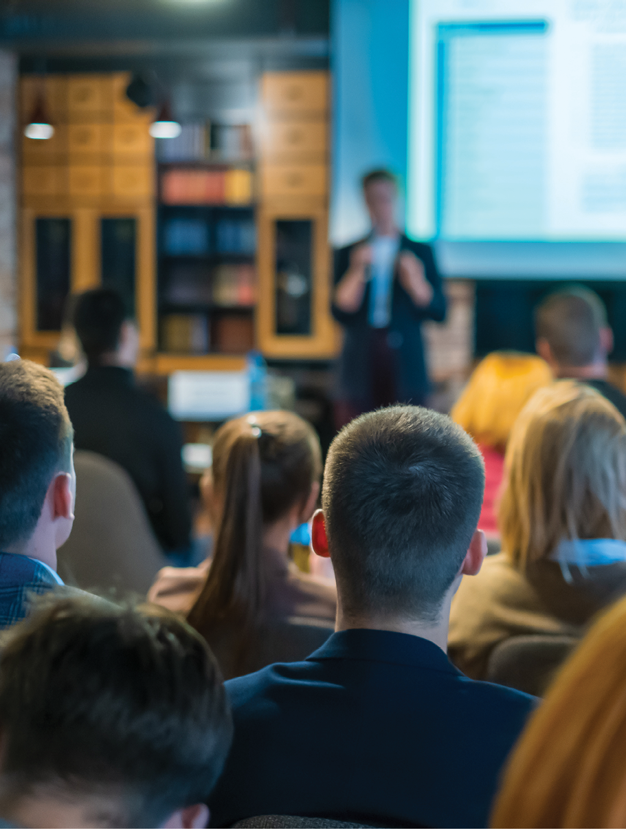 Audience listens lecturer at workshop in conference hall, rear view